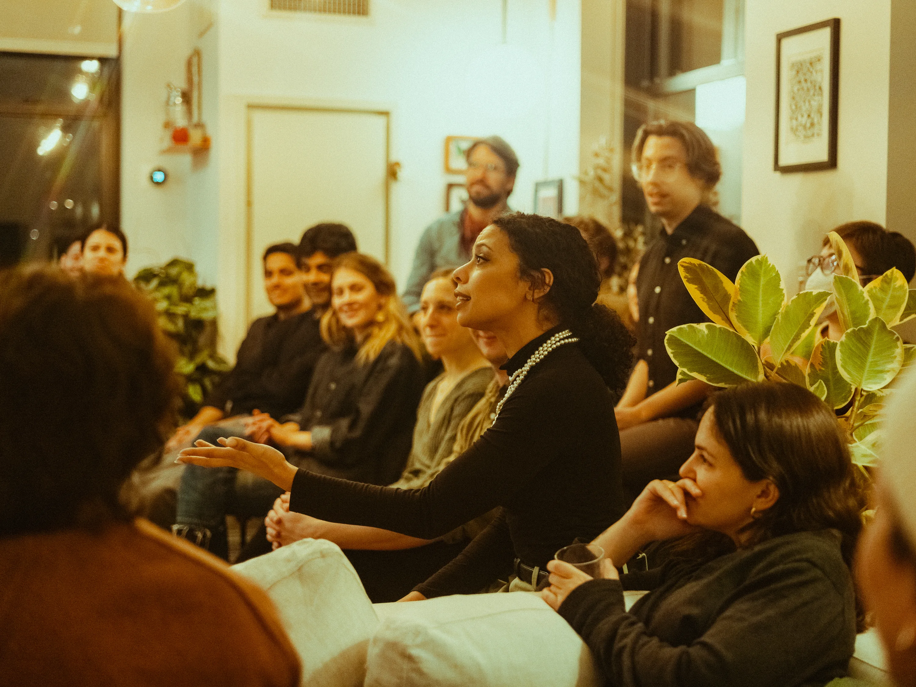 Guests gathered closely around a performance in a living room