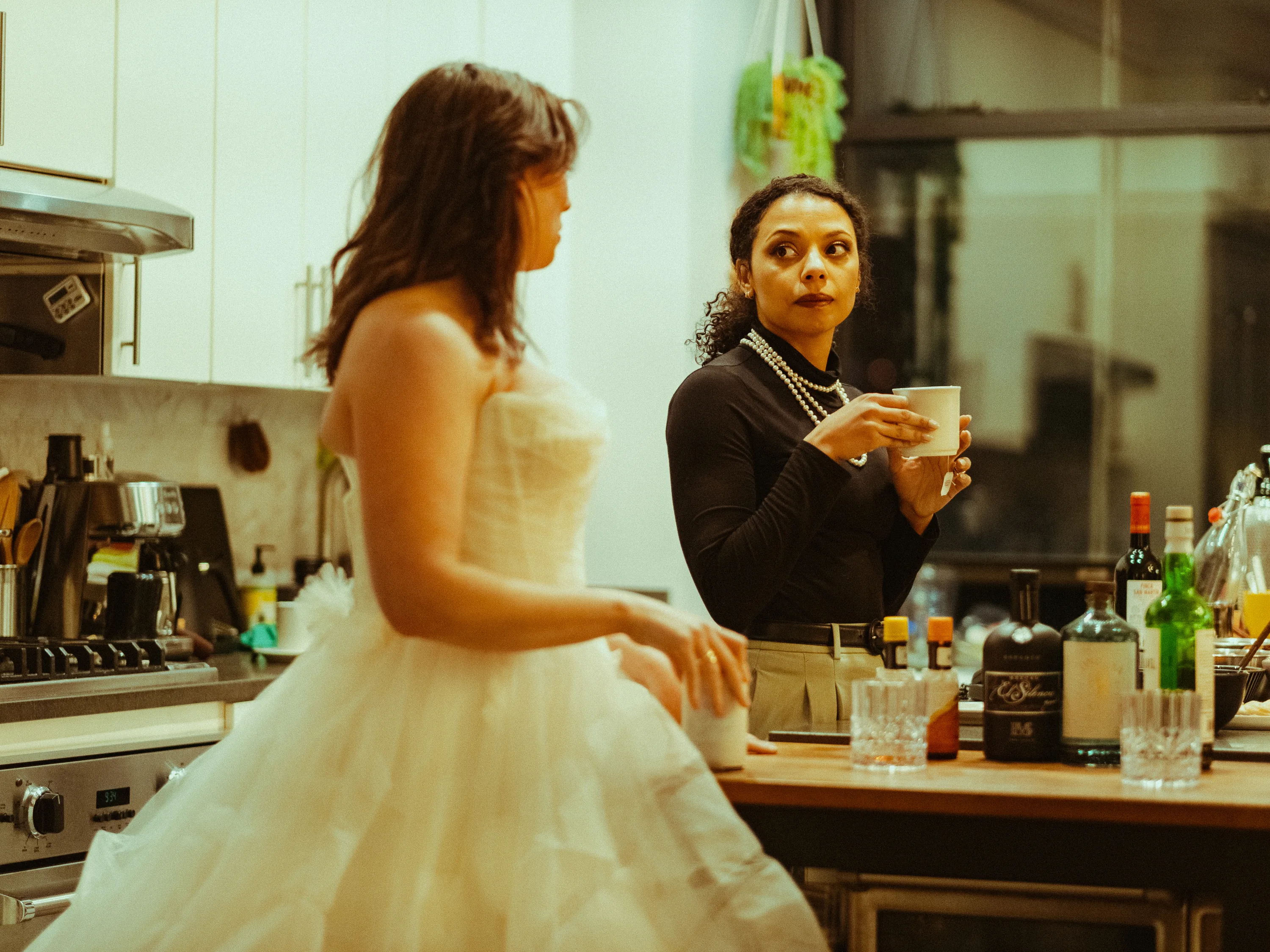 Two actors sharing a tense moment over coffee in a kitchen